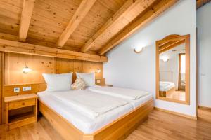 een slaapkamer met een groot bed met een spiegel bij Formsunhof in Siusi