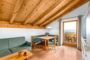 een woonkamer met een tafel en stoelen en een raam bij Formsunhof in Siusi