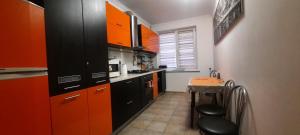 a kitchen with orange and black cabinets and a table at Шикарная 2к квартира Центральный парк Университет 70м in Irpin