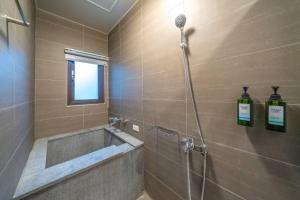 ein Bad mit einer Dusche mit einer Badewanne und einem Fenster in der Unterkunft 無門禁24小時進出-遇見礁溪lll免費停車 in Jiaoxi