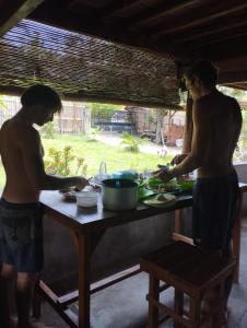 two men standing at a table preparing food at Medya homestay in Pulau Sarang