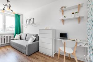 een woonkamer met een bank en een bureau met een laptop bij Super Studio Oldtown in Gdańsk