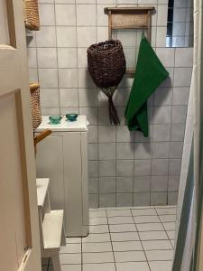 un bagno piastrellato bianco con un cesto appeso al muro di Iloinen taiteilijakoti a Turku