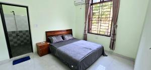 a bedroom with a bed and a glass shower at Hạnh Phương homestay in Tân Hiệp