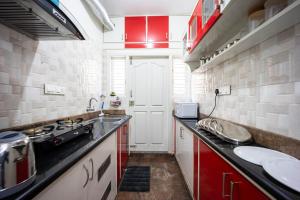 a small kitchen with red cabinets and a sink at HRBR Enclave one BHK with fully furnished in Bengaluru +13 photos
