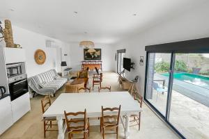 ein Wohnzimmer mit einem Tisch, Stühlen und einem Pool in der Unterkunft Piscine privée proche Thalassothérapie et Mer in Pornic