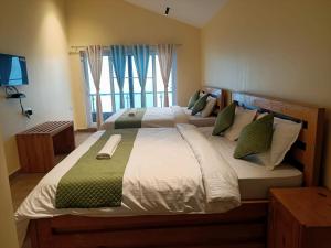 a bedroom with a large bed with green and white pillows at Longwood Resorts in Kotagiri
