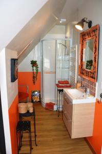 un bagno arancione con lavandino e specchio di La Maison Douce a Saint-Guyomard