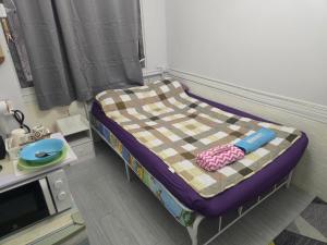 a small bed in a room with a table at 103 Olan Place Apartment with fan and near SkyTrain and free Wi-Fi in Bangkok