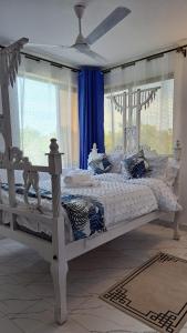 a white bed in a bedroom with blue curtains at Casa Marabella in Diani Beach +56 photos
