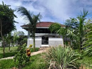a white building with a red roof and palm trees at Casa Marabella in Diani Beach