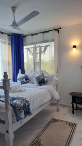 a white bed with blue pillows in a bedroom at Casa Marabella in Diani Beach +143 photos
