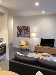 a living room with a black couch and a tv at Marina Tower - Stunning Harbour & City View in Melbourne