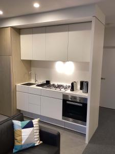 a kitchen with white cabinets and a stove top oven at Marina Tower - Stunning Harbour & City View in Melbourne