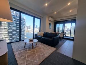 a living room with a couch and a table at Marina Tower - Stunning Harbour & City View in Melbourne
