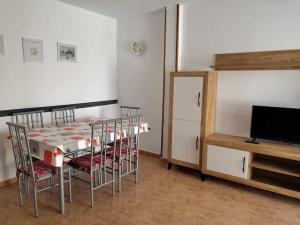 a dining room with a table and chairs and a tv at A H RENTALS Columbra Amplio adosado a 100 mtrs playa Piscina Parking in Peñíscola