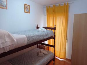 a bedroom with two bunk beds and a yellow curtain at A H RENTALS Columbra Amplio adosado a 100 mtrs playa Piscina Parking in Peñíscola +26 photos