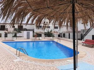 a large blue swimming pool with a straw umbrella at CasAdri Tenerife in Arona