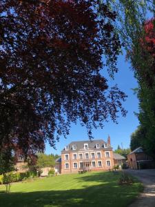 a large house on a grassy field with a tree at Hotel les Champs in Gacé