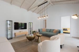 a living room with a blue couch and white chairs at Spacious House with Cottage&Pool in Nafplio