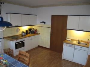 a small kitchen with white cabinets and a sink at Landhaus am Kleeweg in Osteel