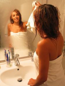
a woman brushing her teeth in front of a mirror at Park Hotel Porto Gaia in Vila Nova de Gaia
