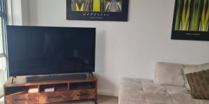 a flat screen tv on a wooden stand next to a couch at Villa 3 Luxe Coastal Escape in Cable Bay