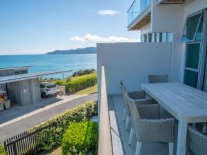 a balcony with a table and chairs and the ocean at Villa 3 Luxe Coastal Escape in Cable Bay