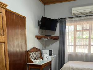 a bedroom with a bed and a tv on the wall at Wooden Door Guesthouse in Brits