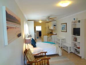 a bedroom with a bed and a desk with a television at Little Gem in Plettenberg Bay