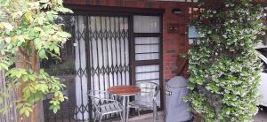 a patio with a table and chairs in front of a door at Little Gem in Plettenberg Bay