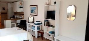 a bedroom with a bed and a tv and shelves at Little Gem in Plettenberg Bay