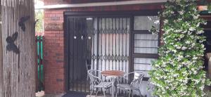 a patio with a table and chairs in front of a door at Little Gem in Plettenberg Bay