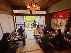 a group of people sitting around a table in a room at くくのちステイ 棚田が見えるゲストハウス in Hakui