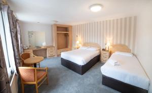 um quarto de hotel com duas camas e uma escrivaninha em Hibernian Hotel & Leisure Centre em Mallow