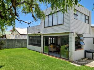 a house with sliding glass doors in a yard at 'Country Beach House' - Traditional Family Vacation Home for 6 - Near Beach in Gordonʼs Bay