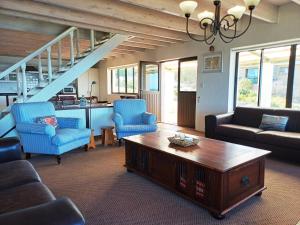 a living room with blue chairs and a coffee table at Whale Watch Cottage in St Helena Bay