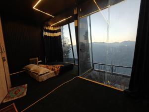 a room with a bed and a large window at INFINITY OTH Cafe and Stays in Kulu