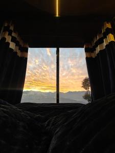 a view of a sunset from a bed with a window at INFINITY OTH Cafe and Stays in Kulu