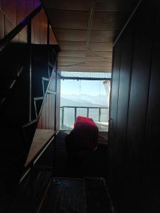 a room with a red chair in front of a window at INFINITY OTH Cafe and Stays in Kulu