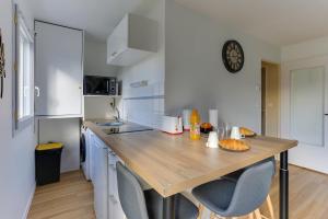 Noyal-Châtillon-sur-SeichにあるL'Escale Bretonne -Studio à 20min de Rennes centreの木製のテーブルと椅子2脚のあるキッチン +5枚の写真