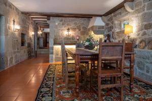 a dining room with stone walls and a wooden table and chairs at Casa de Vilela - casa senhorial exclusiva perto do Porto para até 15 pessoas in Santo Tirso