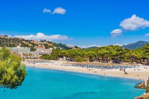 a beach in a resort with people in the water at Villa Calma by Mallorca Infinity in Santa Ponsa