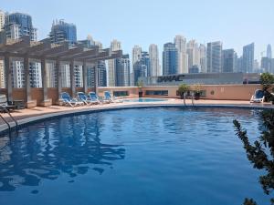 a large swimming pool with chairs and a city skyline at Big Studio Apartment in Dubai Marina Walking to JBR Beach, Cruise and DMCC Metro in Dubai +6 photos