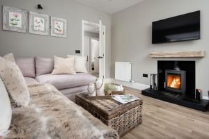 Una sala de estar con un sofá y una chimenea. en Honeysuckle Cottage, Kailzie, en Peebles