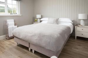 Un dormitorio blanco con una cama grande y una ventana. en Honeysuckle Cottage, Kailzie, en Peebles