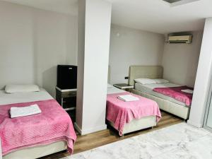 a room with two beds with pink sheets and a tv at Dara Otel in Midyat