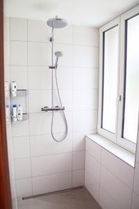 a shower in a white tiled bathroom with a window at einzigartiges stylisches Loft im Grünen in Zell +12 photos