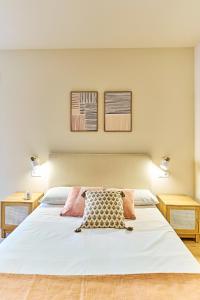 a bedroom with a large white bed with two tables at Apartamentos Delia by gaiarooms in León