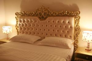 a bed with a gold headboard and two lamps at Crown Hotel Juba in Juba